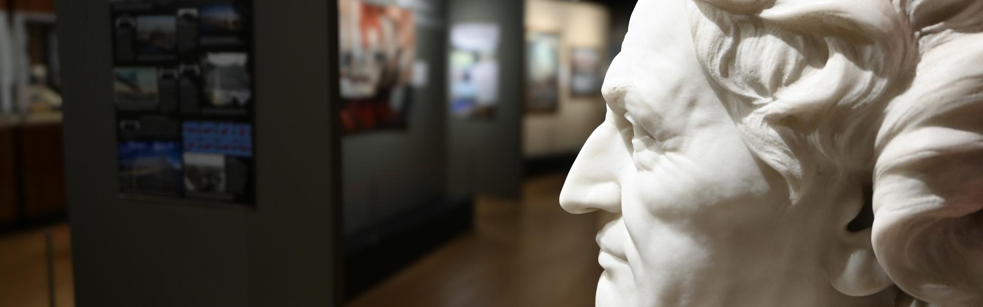 A white marble bust of James Dana on display in the museum gallery