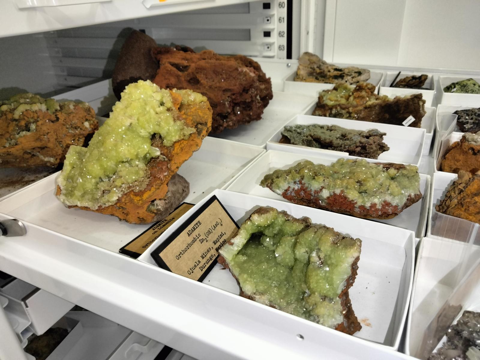 Green mineral specimens in a white metal drawer