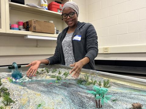 Geosciences graduate student Amina Abdulsalam shows how streams impact the landscape using a stream table feature. Credit: Aagje Eijsink / Penn State. Creative Commons A student works with a stream table in a lab